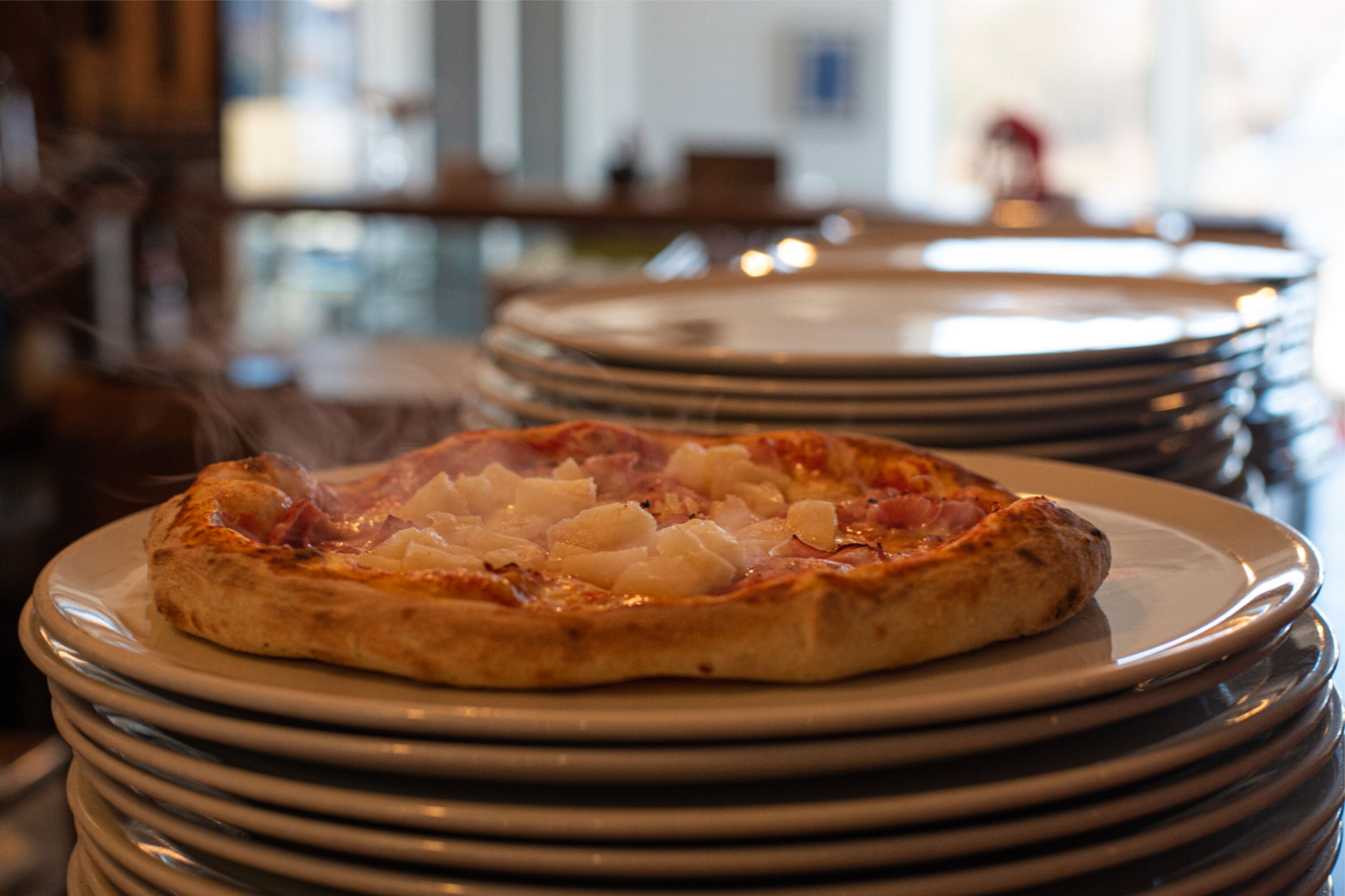 A stack of plates with a pizza on top.