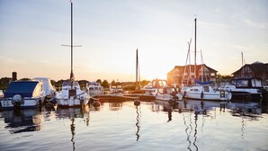 Ein Yachthafen mit mehreren angedockten Booten, ruhigem Wasser und einem Gebäude im Hintergrund.
