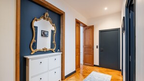 A hallway with a white dresser, a mirror, and a blue wall. - Porcelain Pelouse, by Veeve (Paris)
