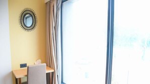 A room with a desk, chair, and a large window with curtains. - Aqua Inn (Kinshasa)