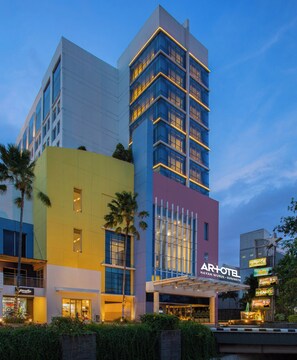 Ein mehrstöckiges Hotel mit modernem architektonischen Design, das einen markanten Eingang mit Glasüren und einer Beschilderung aufweist.