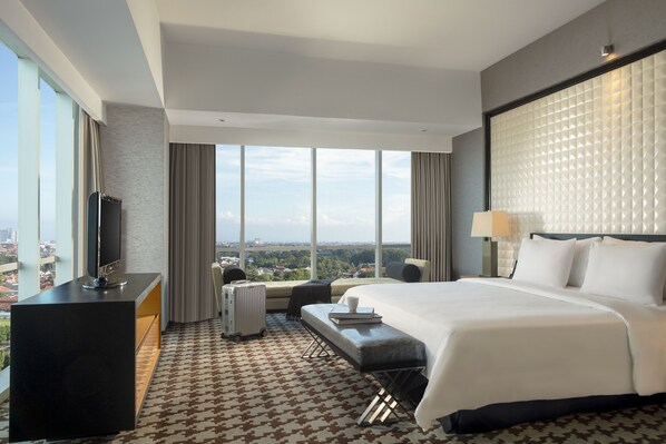 Ein modernes Hotelzimmer mit einem großen Bett, einem Flachbildfernseher, einem Schreibtisch und Blick auf die Stadt.