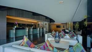 A modern lobby with a reception desk, seating area, and a large vase on a table. - ARTOTEL Grand Prima Surabaya (Surabaya)