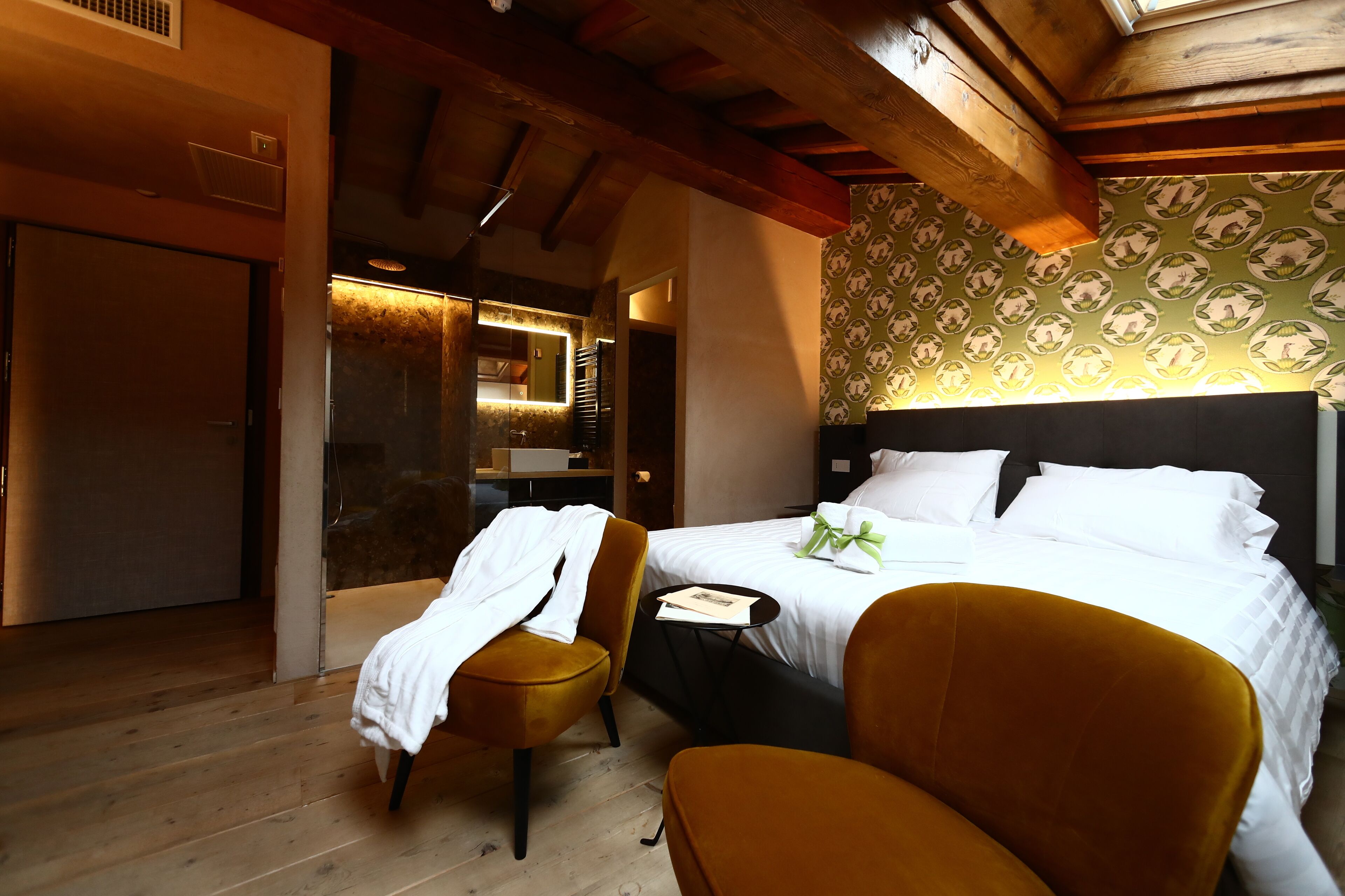 A hotel room with a bed, two chairs, a small table, and a mirror.