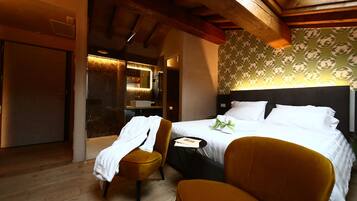 A hotel room with a bed, two chairs, a small table, and a mirror.