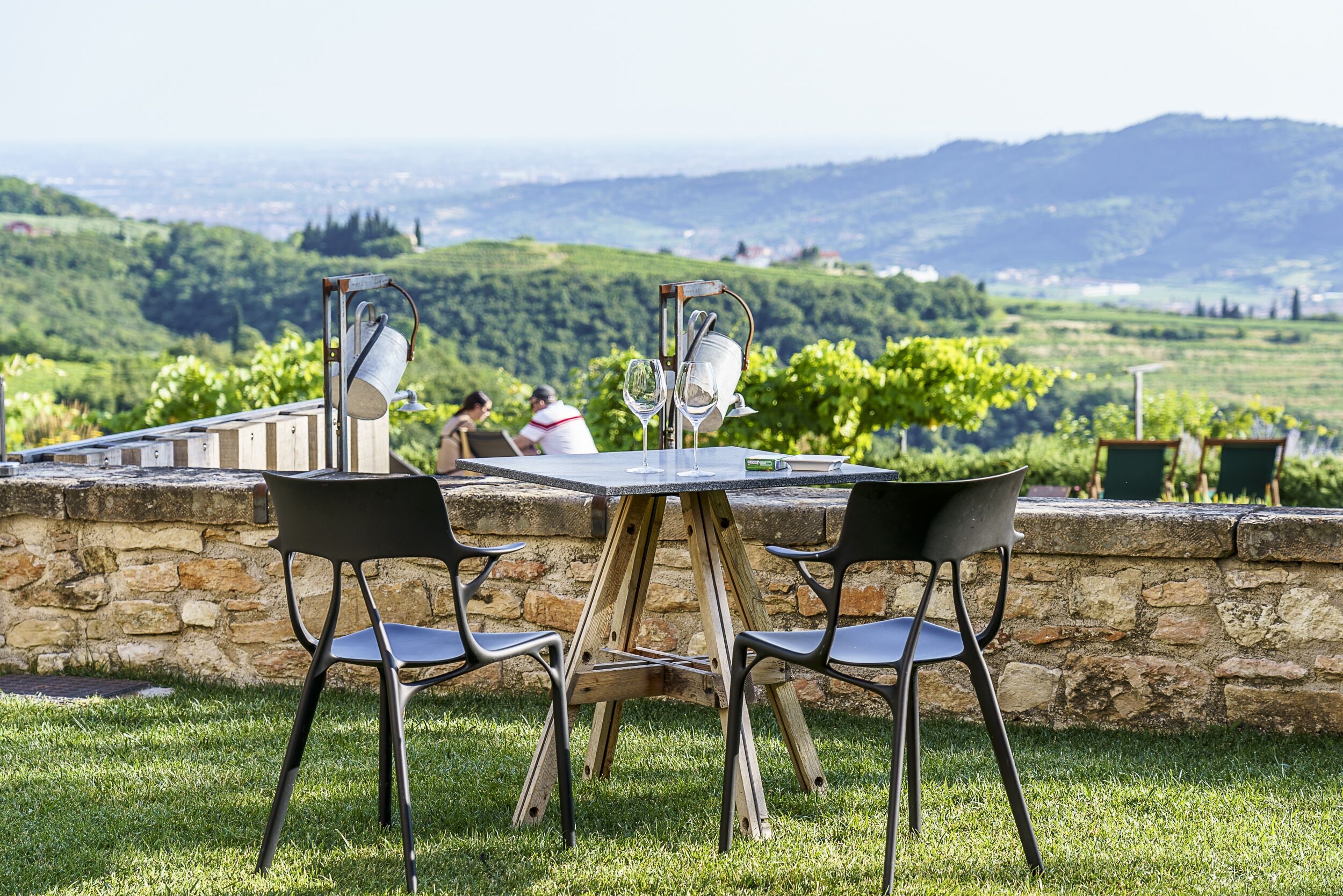 An outdoor dining area with a stone wall and a view of vineyards.