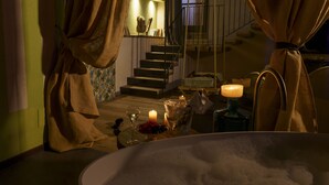 A dimly lit room with a bathtub, a candle, and a fruit bowl on a table. - Villa Balis Crema (Grezzana)