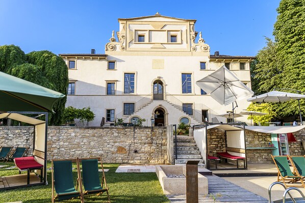 A large building with a stone wall, outdoor seating, and a staircase leading to the entrance. - Villa Balis Crema (Grezzana)