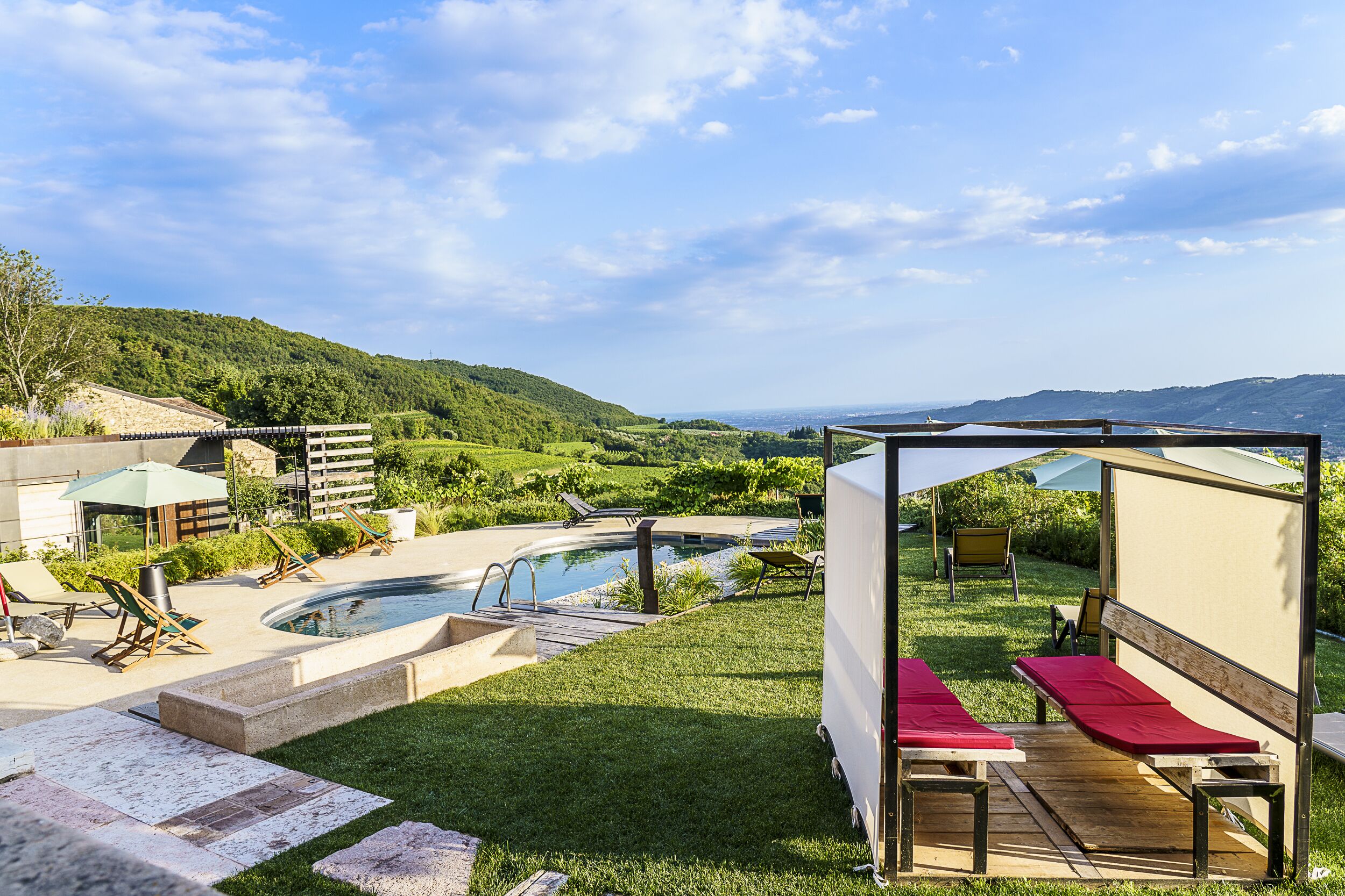 A pool area with lounge chairs, a wooden deck, and a covered seating area.