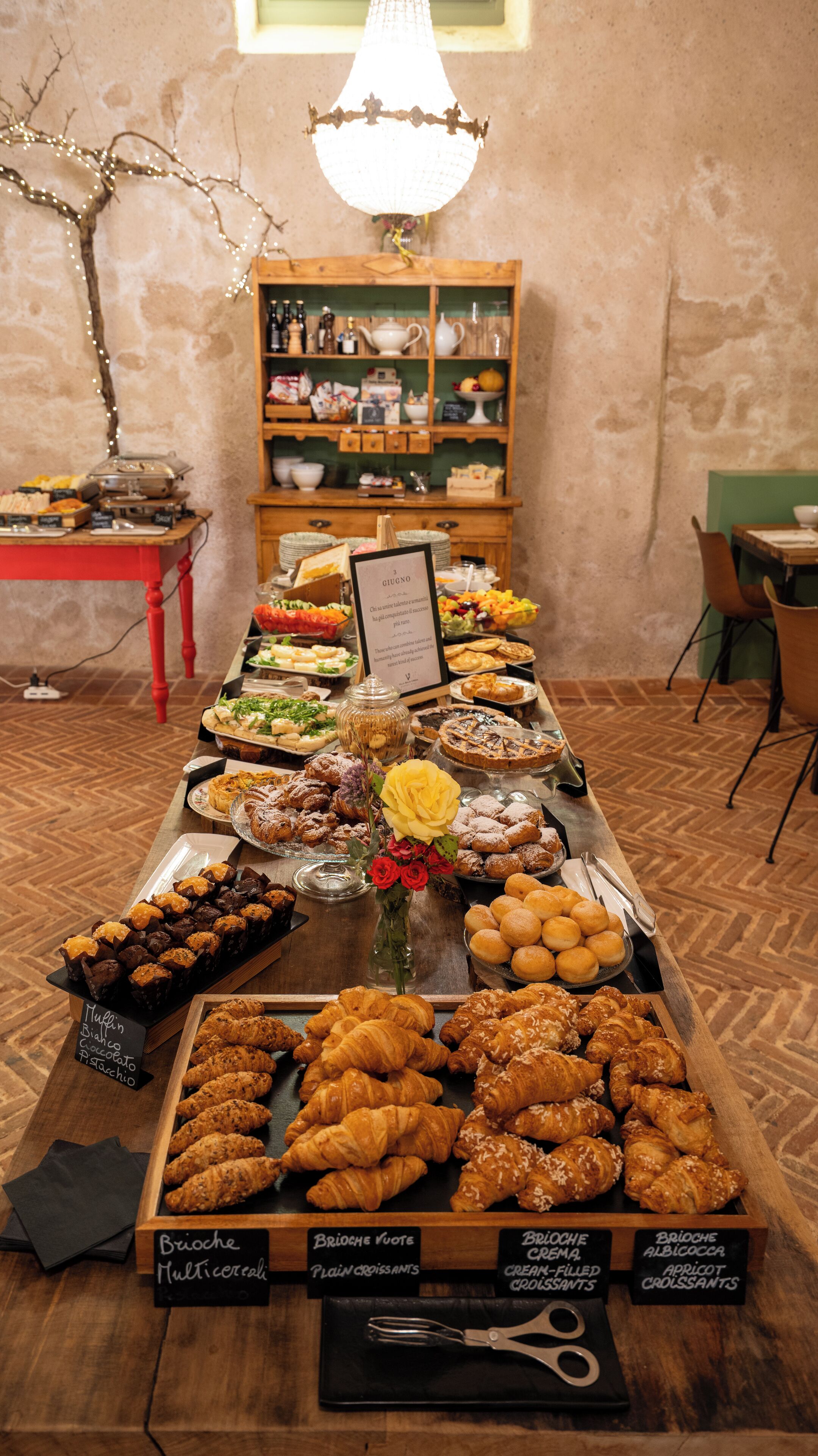 Un bufé con diversos pasteles y postres, una mesa de madera y una araña.