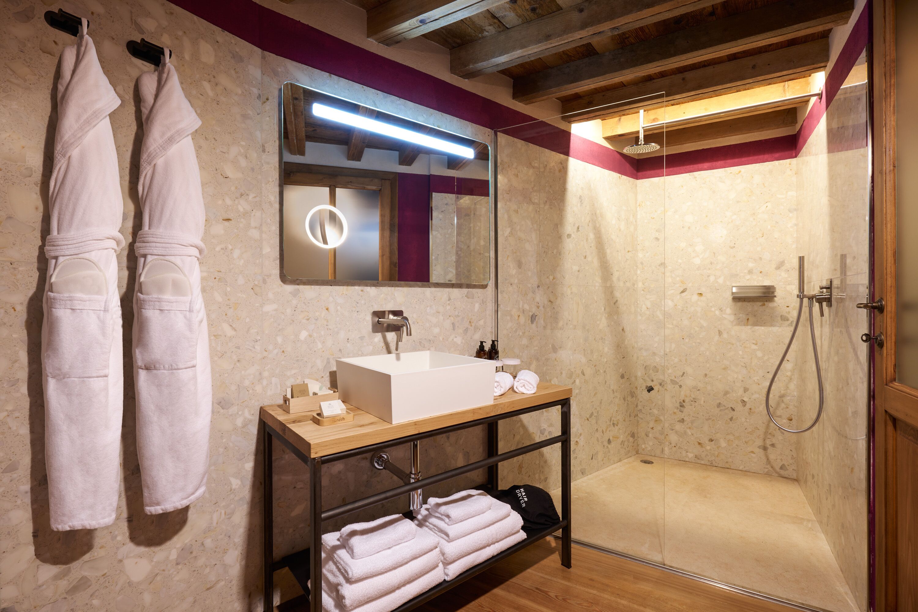 Ein modernes Badezimmer mit einem Holzwaschtisch, einem großen Spiegel und einer bodengleichen Dusche.