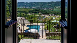 An open doorway leading to a balcony with a pool, surrounded by a fenced area and a view of a hilly landscape. - Villa Balis Crema (Grezzana)