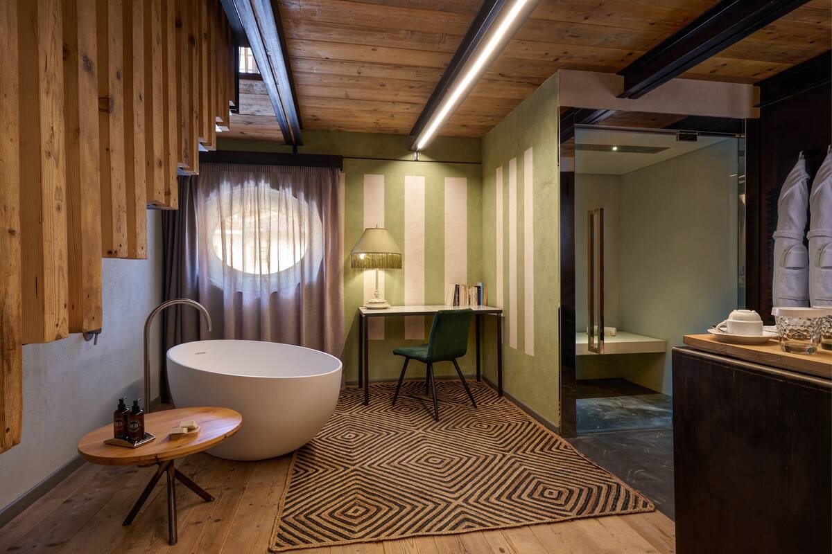 A modern bathroom with a large bathtub, a desk, and a chair.