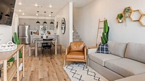 Eine moderne Küche mit Essbereich, einem Ledersessel, einer Couch und einer Treppe.