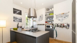 A modern kitchen with a central island, stainless steel appliances, and a hanging pot rack.