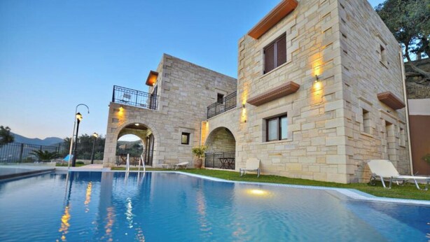 Un edificio de piedra con piscina, mobiliario exterior y vistas a las montañas.