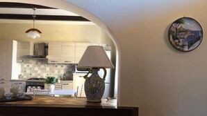 Una cocina de diseño moderno, con una isla central con lámpara, un colgador de techo y un plato decorativo en la pared.