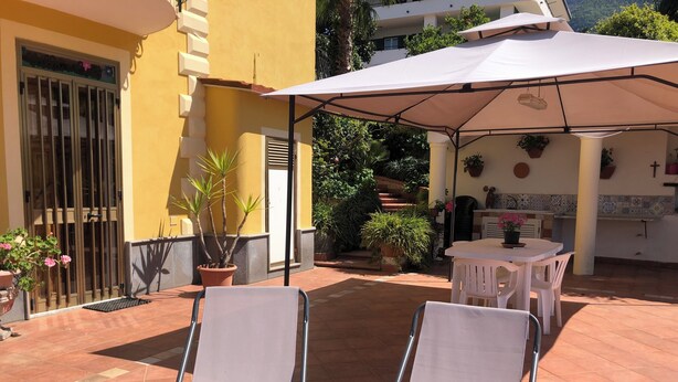 Un patio con dos sillones, una mesa y una sombrilla.