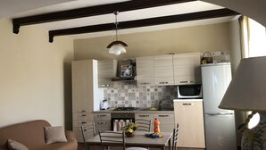 Cocina moderna con comedor, que incluye un sofá, una mesa de comedor, sillas y una lámpara colgante.