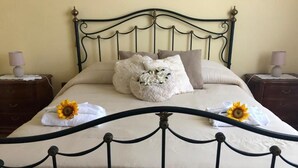 Una cama con estructura metálica, ropa de cama color beige y almohadas decorativas.