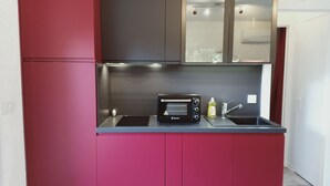 A compact kitchen with a built-in microwave, a sink, and a stovetop. - Superb T2 on garden level in private residence with swimming pool (Cap d'Agde)