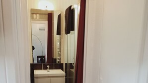 A narrow hallway leading to a bathroom with a white sink, mirror, and towel rack. - Superb T2 on garden level in private residence with swimming pool (Cap d'Agde)