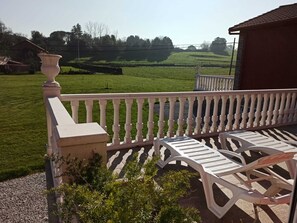 Un balcon avec des balustrades blanches et deux chaises en plastique blanches.