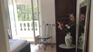 A bedroom with a bed, a chair, a small table with a vase, and a wardrobe. - Beautiful villa spatieuse quiet residential area (LES ADRETS DE L' ESTEREL)