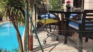 A poolside area with a table and chairs, a palm tree, and a building with a number '7' on it. - Beautiful villa spatieuse quiet residential area (LES ADRETS DE L' ESTEREL)