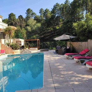Una piscina con lettini e un gazebo.