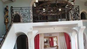 A spacious living area with a high ceiling, a chandelier, and a staircase with ornate railings. - Beautiful villa spatieuse quiet residential area (LES ADRETS DE L' ESTEREL)