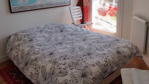 Een slaapkamer met een bed, een kaart aan de muur, een stoel en uitzicht op buiten.