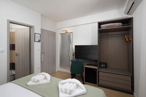 A hotel room with a bed, a TV, a closet, and a desk.