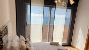Ein modernes Schlafzimmer mit einem großen Bett, einem Nachttisch und Blick auf einen Balkon.