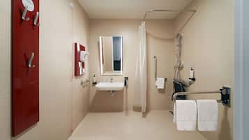 Un baño moderno con lavamanos, espejo, ducha e inodoro.