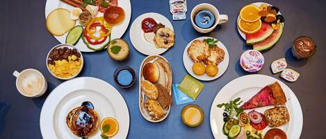 A variety of breakfast items including pancakes, eggs, toast, and fruit arranged on plates.