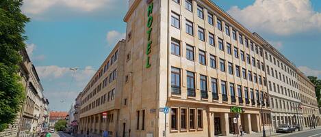 Un hôtel à plusieurs étages, reconnaissable à son grand panneau « HÔTEL » sur la façade, qui présente un style architectural classique avec de grandes fenêtres et un toit plat.