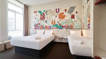 A hotel room with a large bed, two bedside tables, a chair, and a mural on the wall depicting a cityscape.