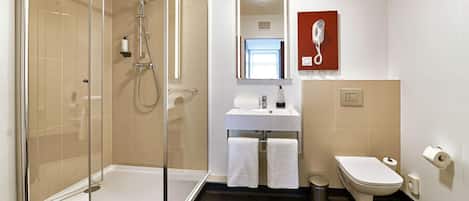Un baño moderno con ducha envuelta en vidrio, un lavamanos blanco, un espejo y un inodoro.