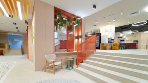 Un intérieur moderne avec un escalier, un coin salon et un comptoir d’accueil.