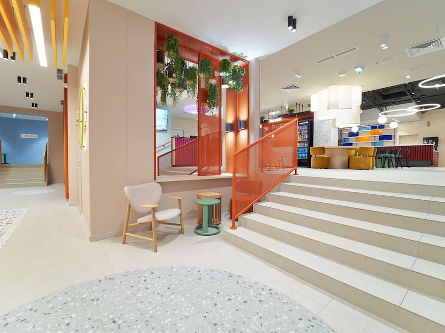 A modern interior with a staircase, seating area, and a reception desk.