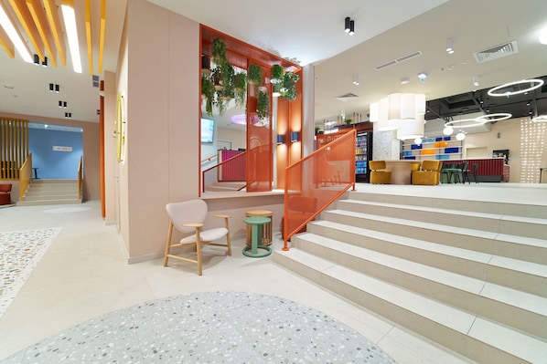 A modern interior with a staircase, seating area, and a reception desk. - B&B Hotel Poznań Old Town (Poznan)