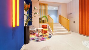 Un hall d’hôtel moderne avec un escalier, un espace salon et une plante.