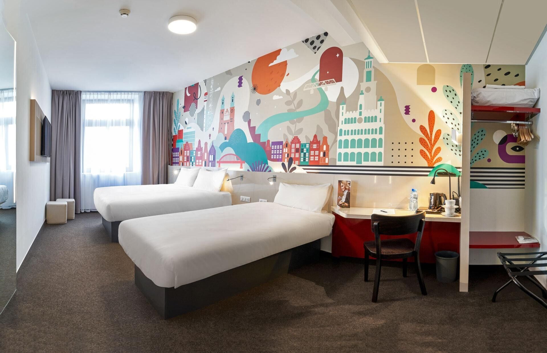 A hotel room with two beds, a desk, and a chair.
