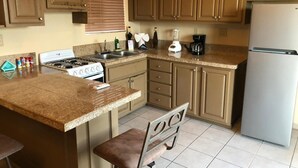 Una cocina con encimeras de granito, estufa a gas, refrigerador y armarios de madera.