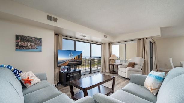 Un salon spacieux doté d’un grand téléviseur à écran plat, d’un canapé confortable, d’une table basse et offrant une vue sur la mer grâce à de grandes fenêtres.