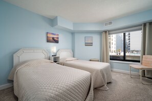 A hotel room with two beds, a window with a view of buildings, and a chair by the window. - First Floor, two bedroom 2 bath with ocean views! (Ocean City)