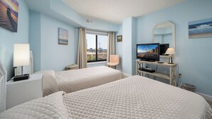 Une chambre d’hôtel avec deux lits, une télévision, un bureau avec un ordinateur et une fenêtre donnant sur la ville.