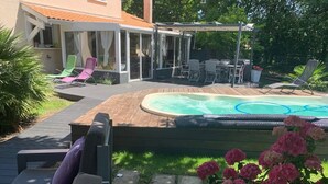 Un jardin avec un jacuzzi, un espace salon extérieur et une terrasse couverte.