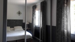 Une chambre à coucher avec un lit, une table de chevet, une lampe et une fenêtre avec des rideaux.